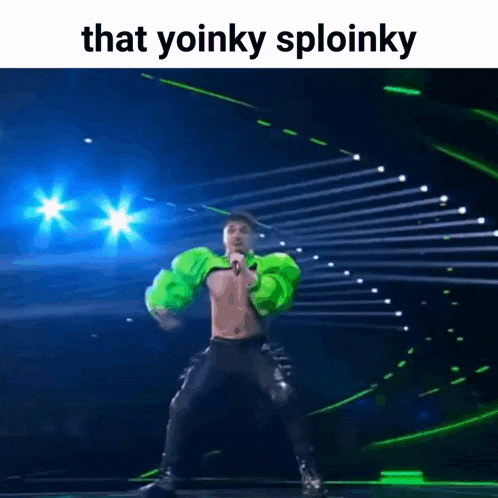 a man in a green jacket is singing into a microphone while dancing on a stage .