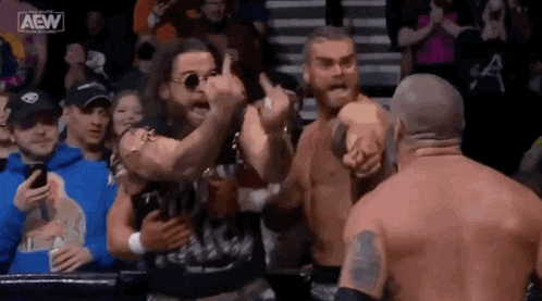 a group of men are standing next to each other in a wrestling ring giving each other thumbs up .
