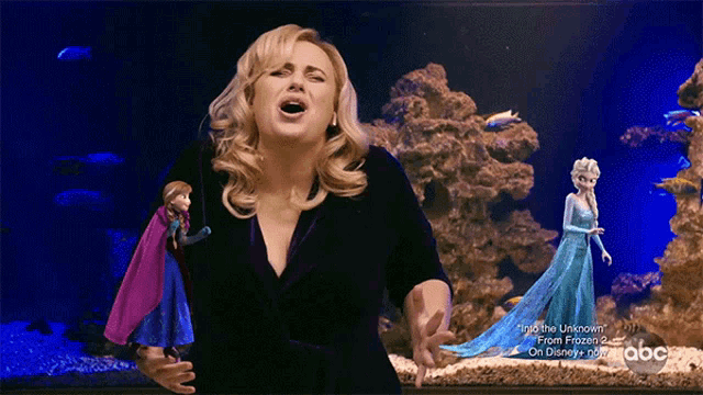 a woman singing in front of an aquarium with a frozen 2 advertisement on the bottom