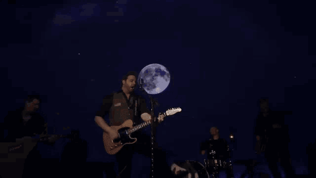 a man is playing a guitar and singing into a microphone on a stage .