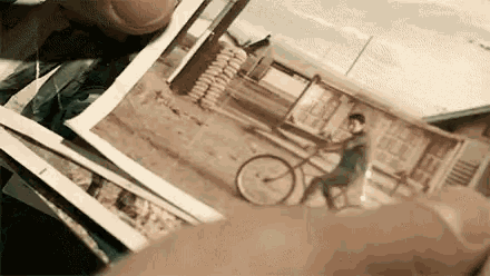 a person is holding a picture of a man riding a bike .