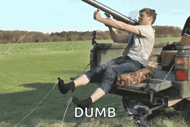a man is sitting in the back of a truck holding a large rocket launcher .