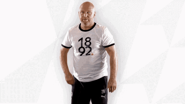 a bald man wearing a white shirt that says 18 92