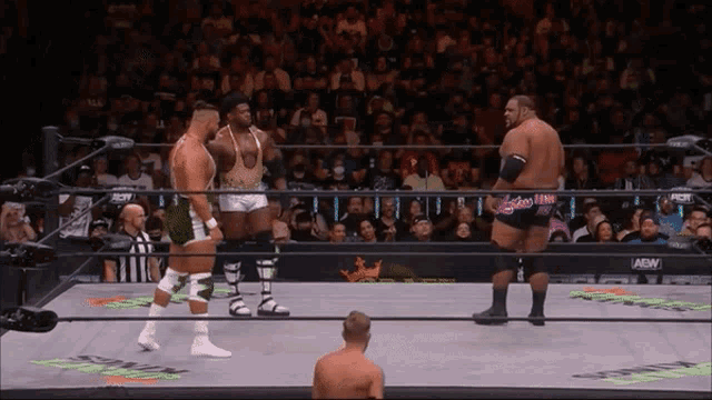 three wrestlers are in a ring with adn written on the wall