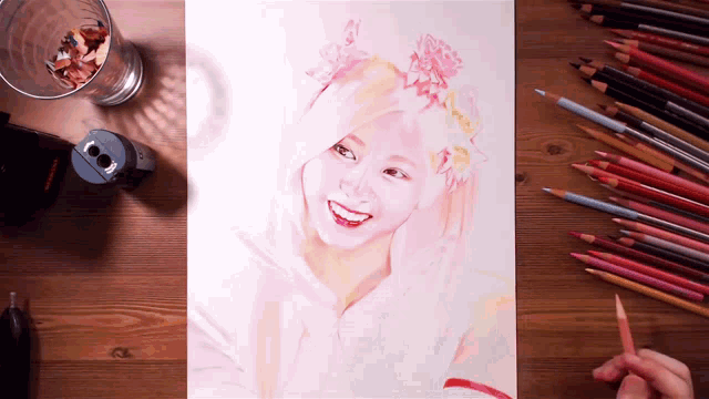 a drawing of a girl with flowers in her hair is on a table with colored pencils