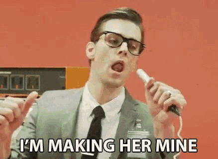 a man in a suit and tie is holding a microphone in his hand and saying i 'm making her mine .