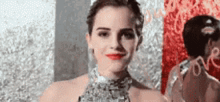 a woman in a dress is smiling and looking at the camera in front of a mirror .