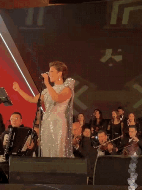a woman in a sequined dress singing into a microphone