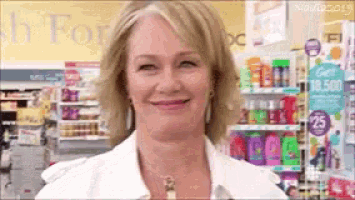 a woman in a white shirt is smiling in front of a sign that says 25