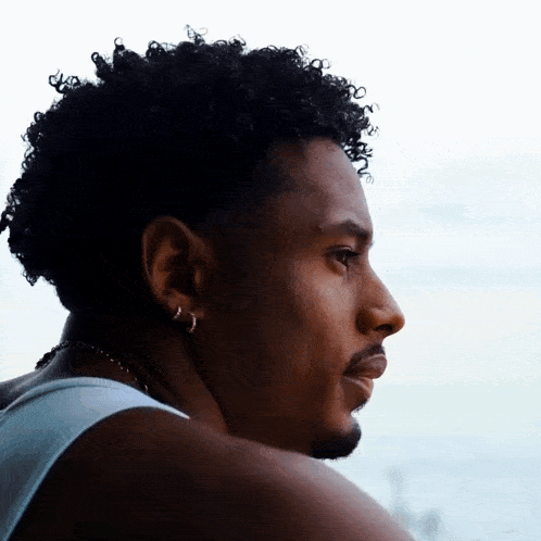 a man with curly hair and a beard is wearing hoop earrings