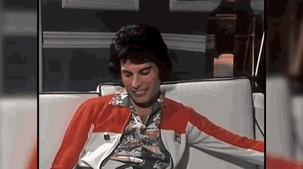 a man wearing a red and white jacket is sitting on a couch