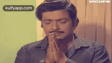 a man with a mustache is praying with his eyes closed .
