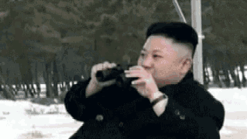 a man is drinking from a bottle while looking through binoculars .
