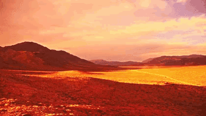 a desert with mountains in the background and a red sky