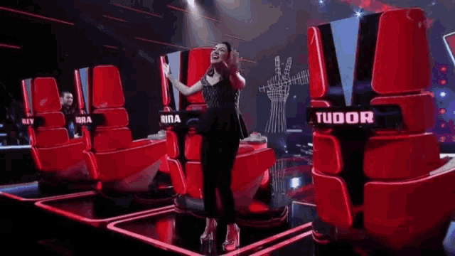 a woman is dancing on a stage in front of a tudor chair .