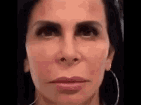 a close up of a woman 's face with black eyebrows and earrings .