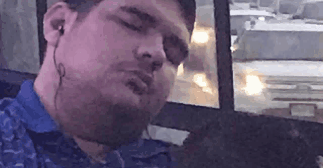 a man wearing ear buds is sleeping on a bus .
