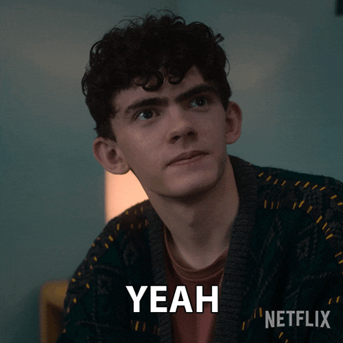 a man with curly hair is wearing a green sweater and says yeah