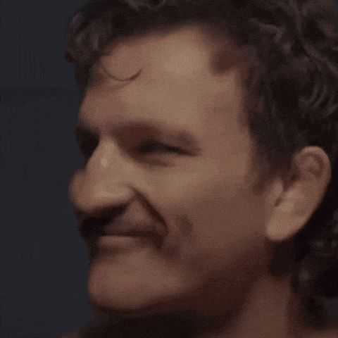 a close up of a man 's face with a mustache smiling