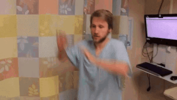 a man in a hospital gown is dancing in front of a monitor and keyboard