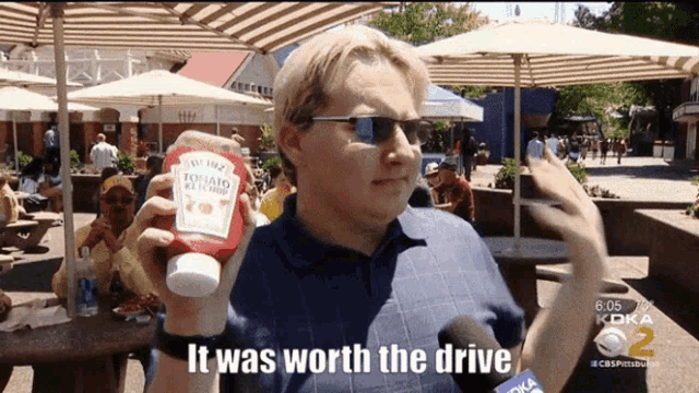 a man holding a bottle of ketchup with the words it was worth the drive below him