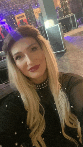 a woman takes a selfie in front of a stage with a purple light behind her