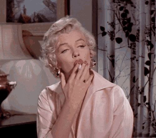 a woman covering her mouth with her hand while smoking a cigarette