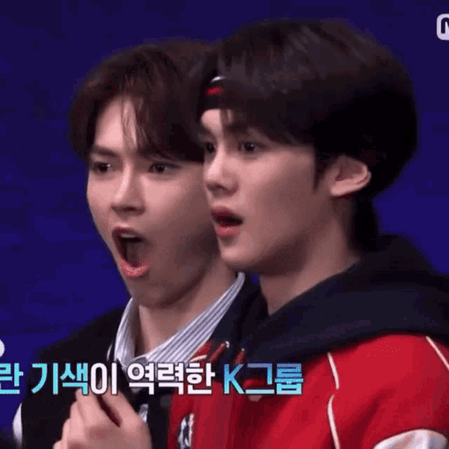 a couple of young men are standing next to each other with their mouths open and one of them is wearing a headband .