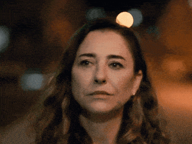 a close up of a woman 's face with a blurry background of lights