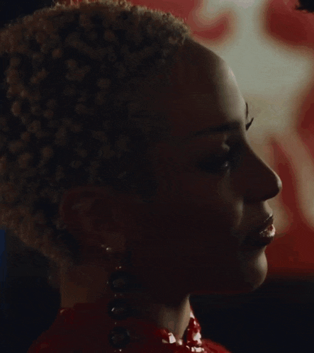 a close up of a woman 's face wearing earrings and a red dress .