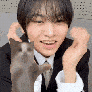 a man in a suit and tie is holding a cat in his hands