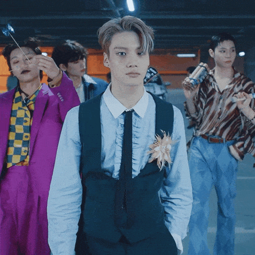a man in a suit with a flower on his chest stands in a line with other men