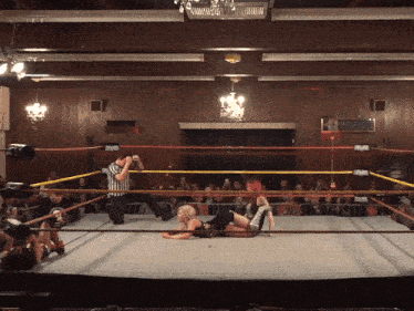 a wrestler is laying on the ground in a ring with a referee