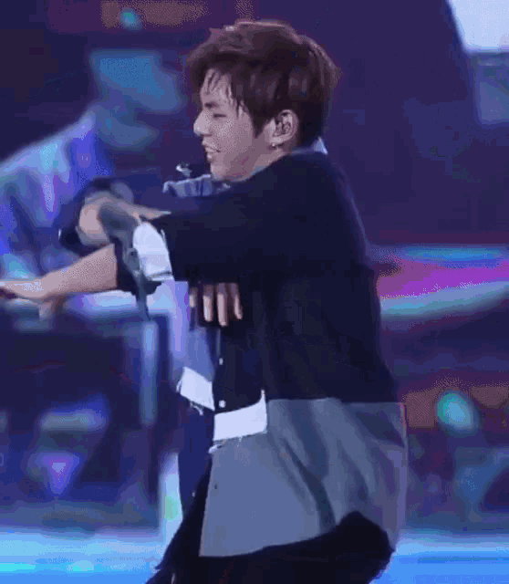 a man in a suit is dancing on a stage in front of a blue background .
