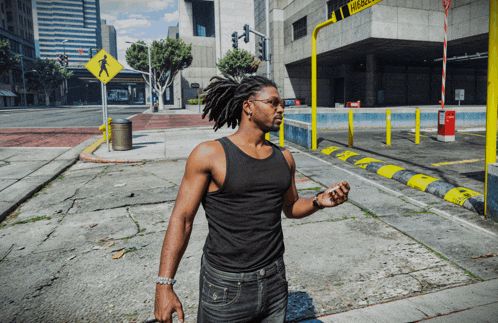 a man in a black tank top is walking down a street