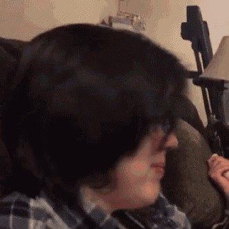 a woman with short hair is sitting on a couch with a lamp in the background