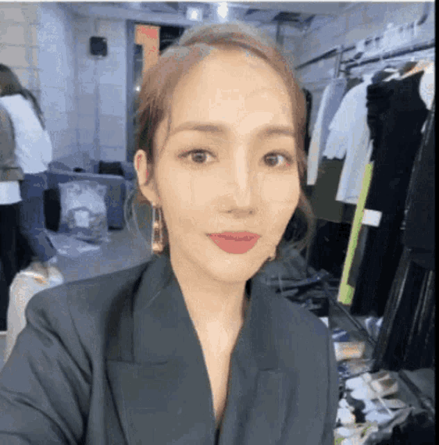 a woman taking a selfie in a room with clothes on display