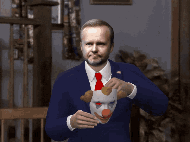 a man in a blue suit and red tie is holding a clown mask