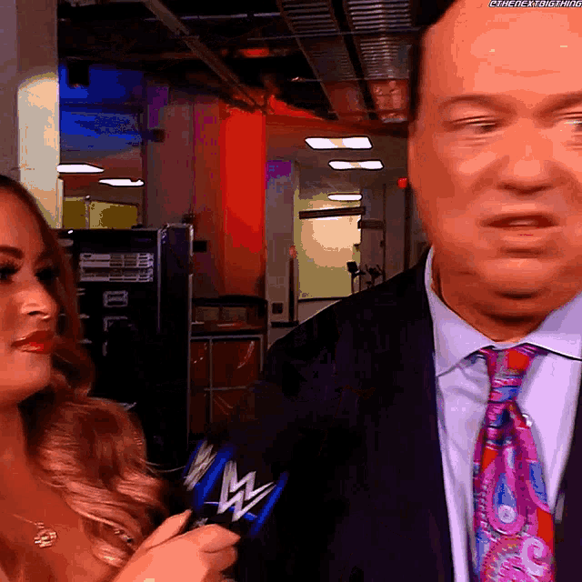 a man in a suit and tie is being interviewed by a woman who is holding a microphone with the w logo on it