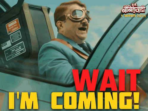 a man in a suit and goggles is driving a car with the words wait i 'm coming in red