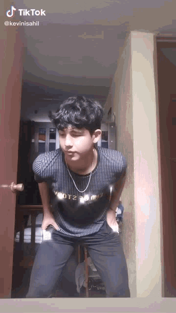 a young man is standing in a room with his hands in his pockets and a tiktok watermark on the bottom right