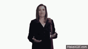 a woman in a black jacket and a purple scarf is making a gesture with her hands .
