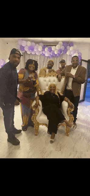 a group of people posing for a picture including a woman sitting in a chair