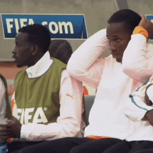 two men sit in front of a sign that says fifa