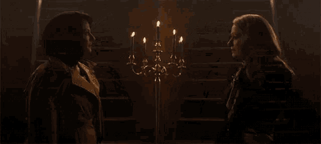 two women are standing next to each other in a dark room with candles .