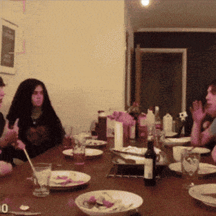 a group of people are sitting at a table with plates and a bottle of wine on it