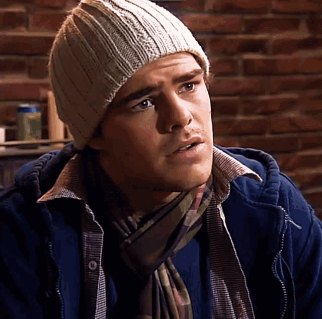 a man wearing a beanie and a scarf looks to his left