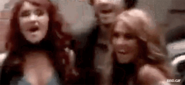 a group of women are standing next to each other and screaming .