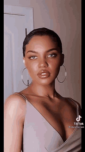 a woman wearing hoop earrings and a plunging neckline is looking at the camera .