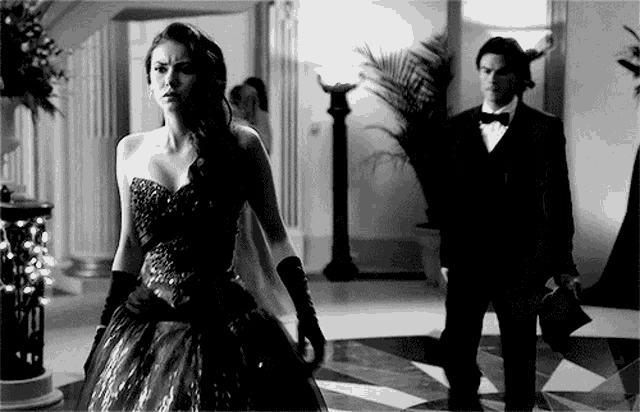 a black and white photo of a woman in a dress and a man in a tuxedo .